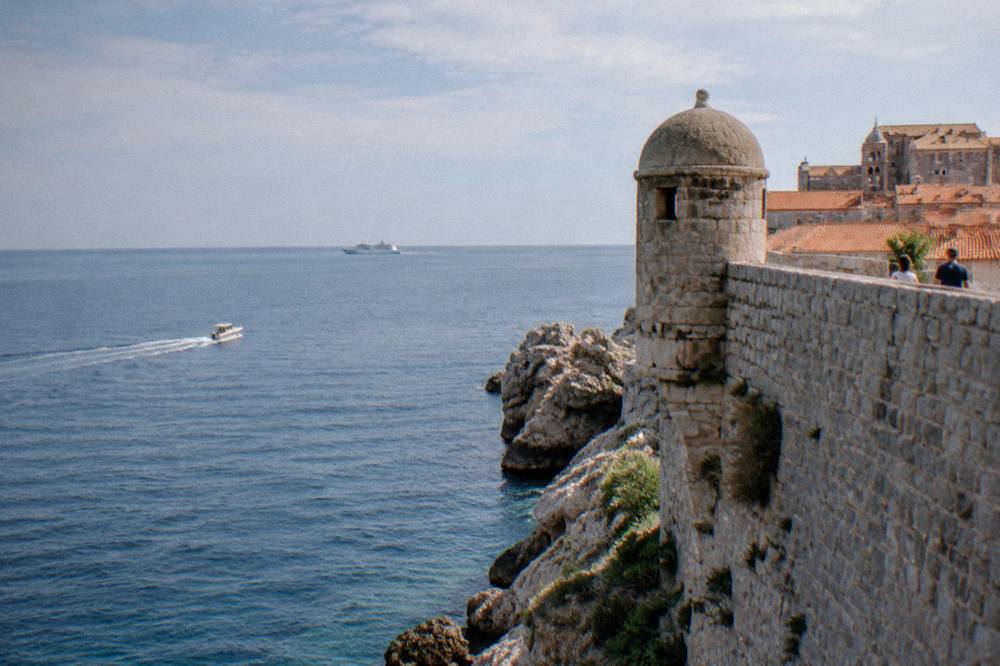 City wall corner tower above the sea with a distant ferry