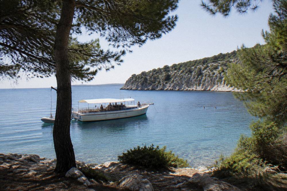 Excursion boat anchored in a sheltered Dugi Otok bay with limestone cliffs