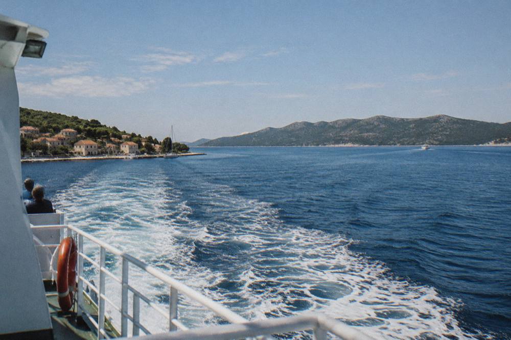 Calm channel crossing with a ferry wake and island ridge ahead
