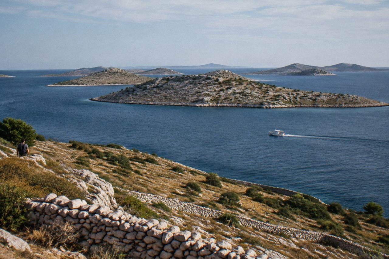 Bare limestone Kornati islands across deep blue water with a small boat