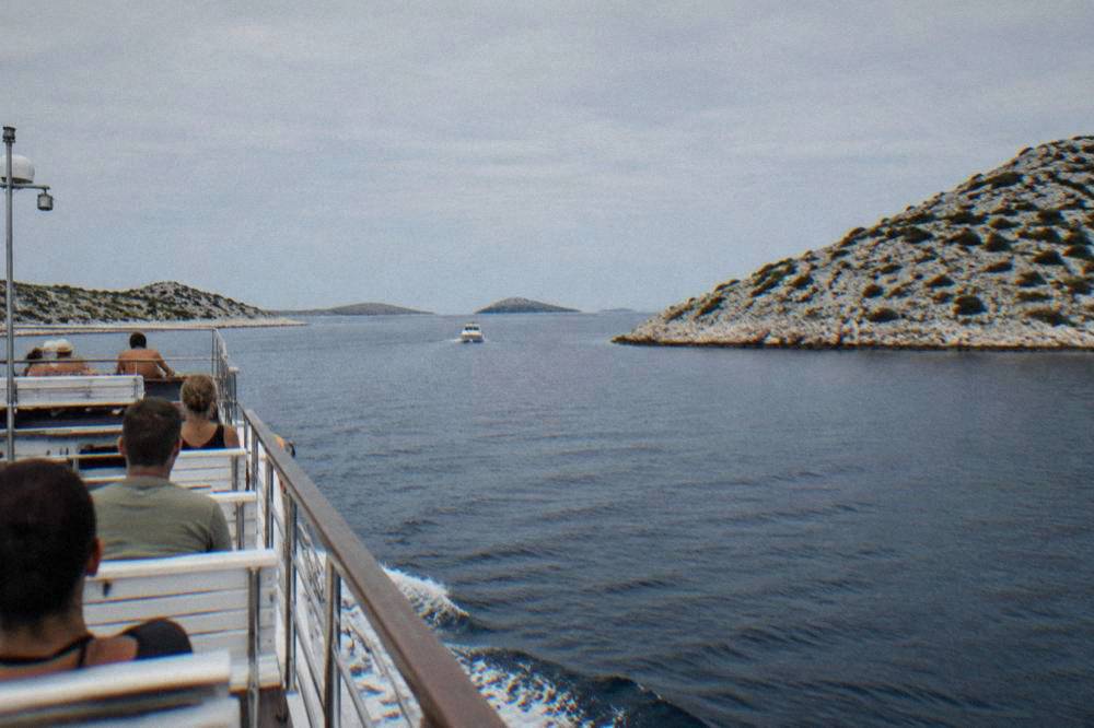 Excursion boat gliding between low bare Kornati islands on a clear day