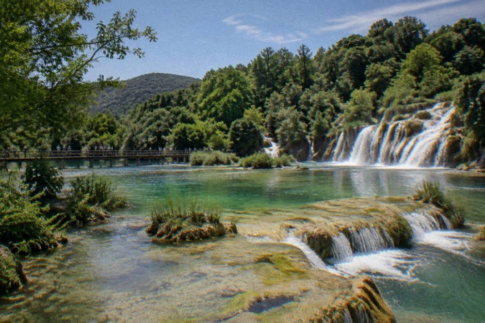 Wide view of travertine terraces and green pools with a distant boardwalk