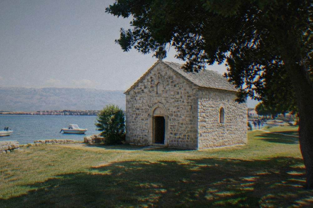 Tiny pale stone pre-Romanesque church with a small arched door in Nin