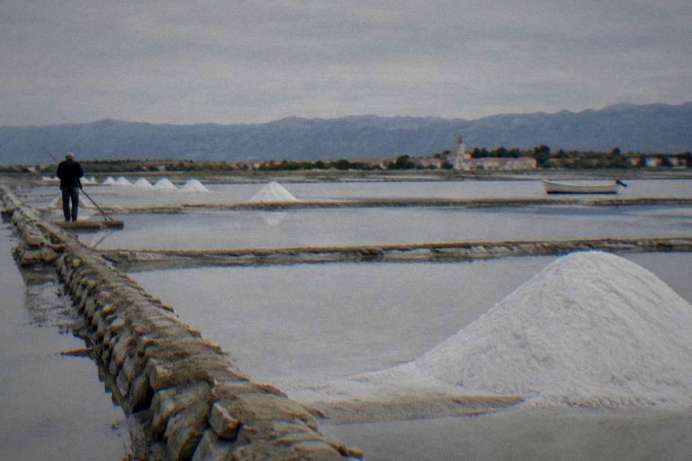 Salt pans with shallow pools and heaps of white salt crystals