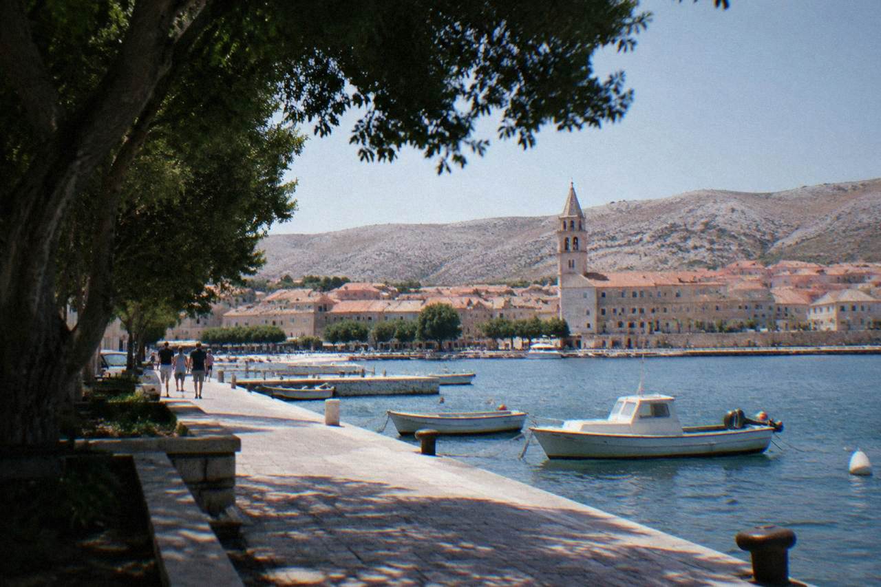 Pag Town waterfront with a stone quay, boats and church tower