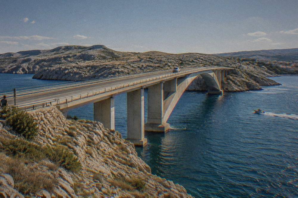 Bridge over a narrow strait with arid hills and blue water
