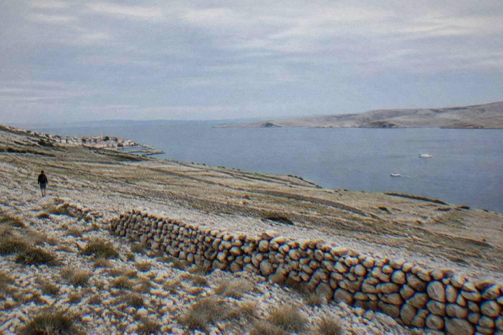 Dry stone walls across a bare limestone slope on Pag with the sea beyond