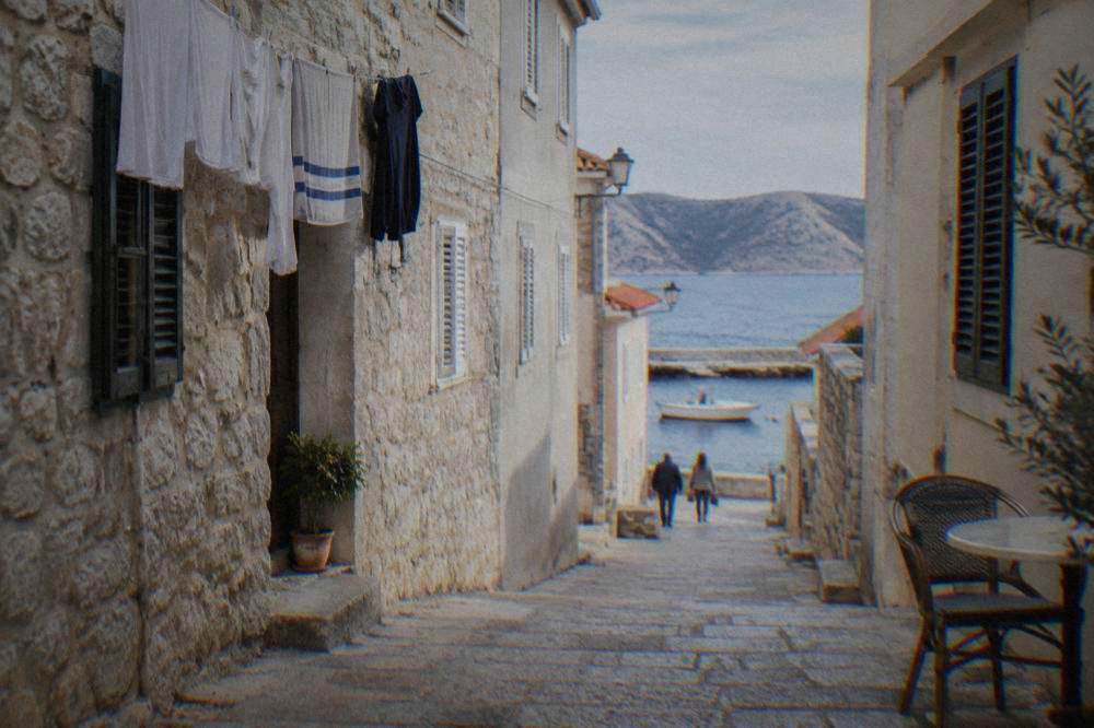 Quiet stone lane in Pag Town with pale houses and a cafe chair
