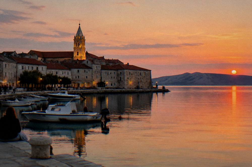 Pag Town waterfront at evening with a lit bell tower and calm water