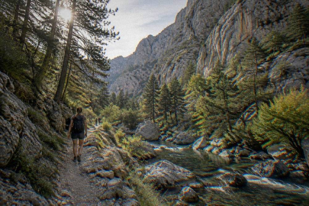 Hiker seen from behind on a narrow path below towering cliffs