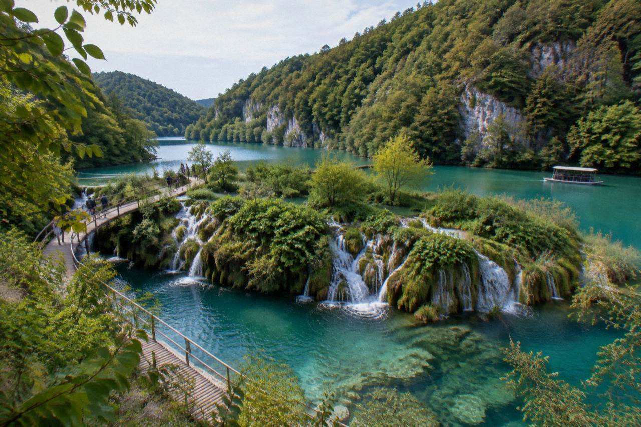 Turquoise terraced lakes with waterfalls and a wooden boardwalk in forest