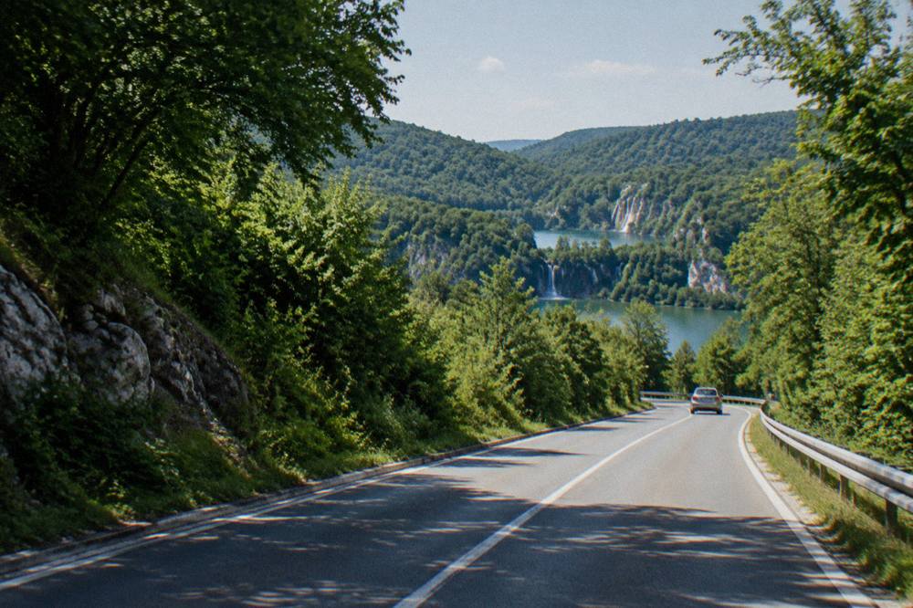 Inland road through green hills and forest toward the park