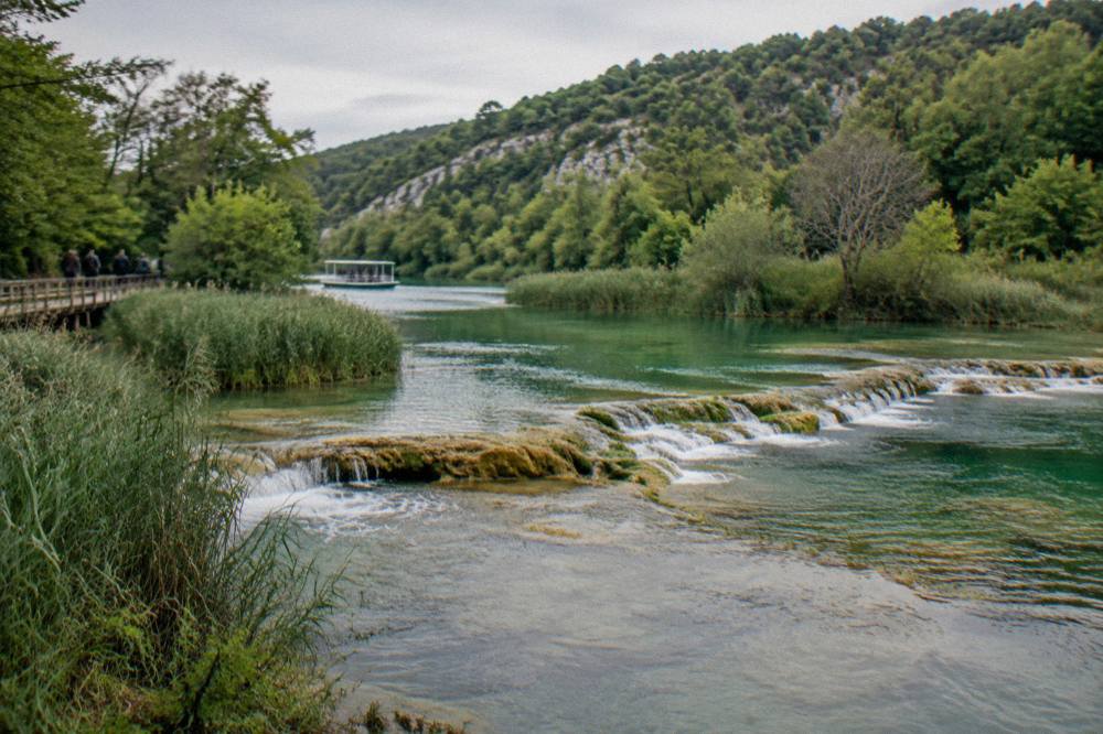 Quiet green river valley with calm water and travertine ledges at Krka