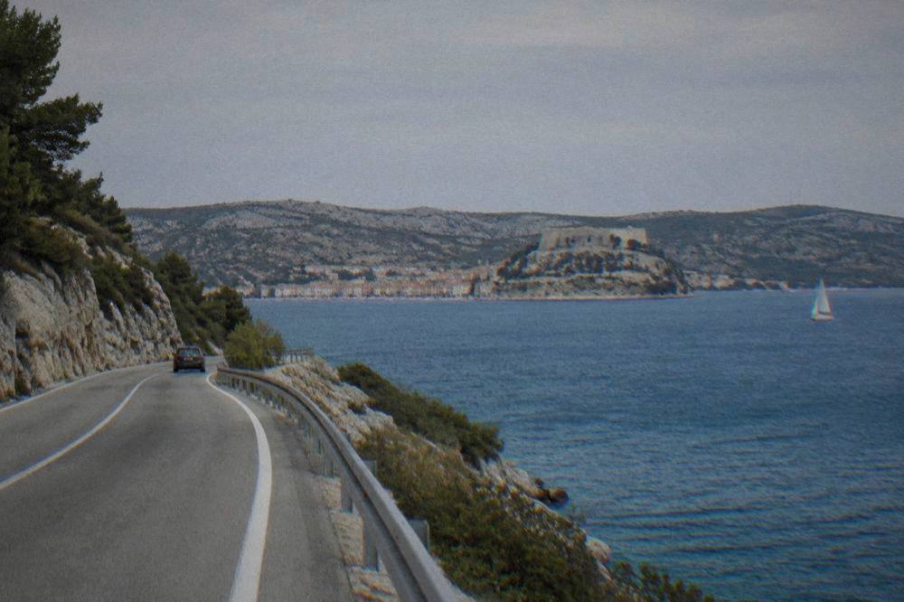 Coastal road with blue sea and bare limestone hills in summer light