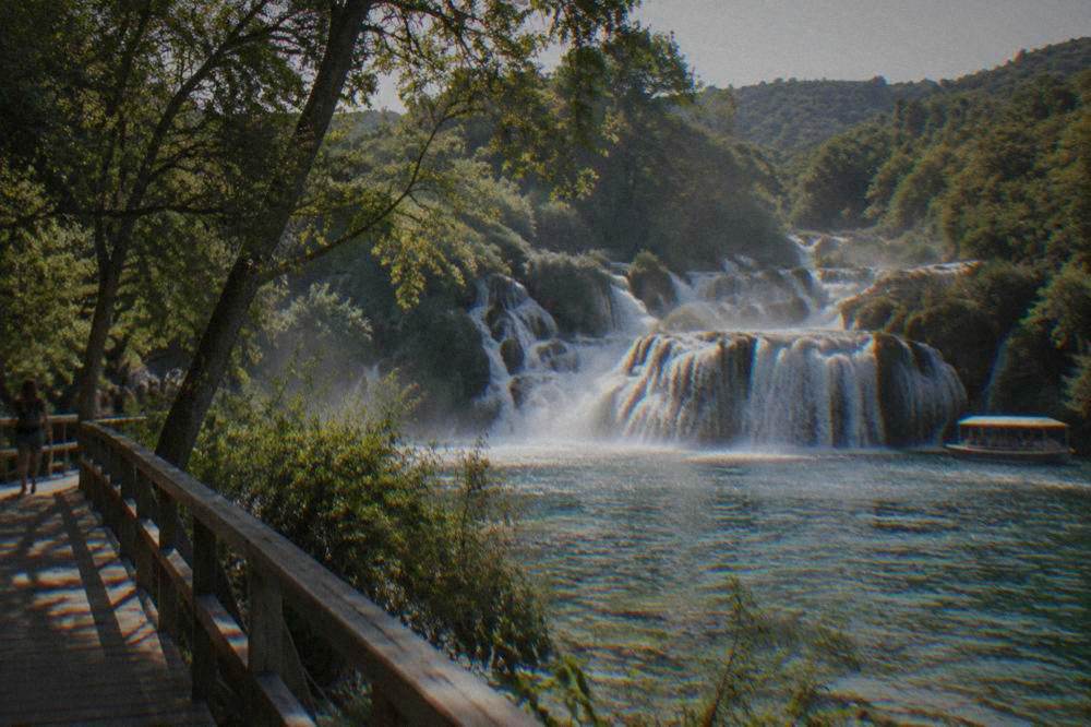 Travertine waterfalls tumbling into a pool with a wooden walkway