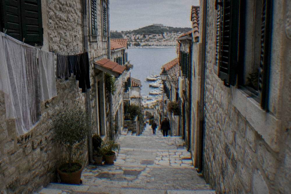 Steep stone alley with worn steps and green shutters in Sibenik