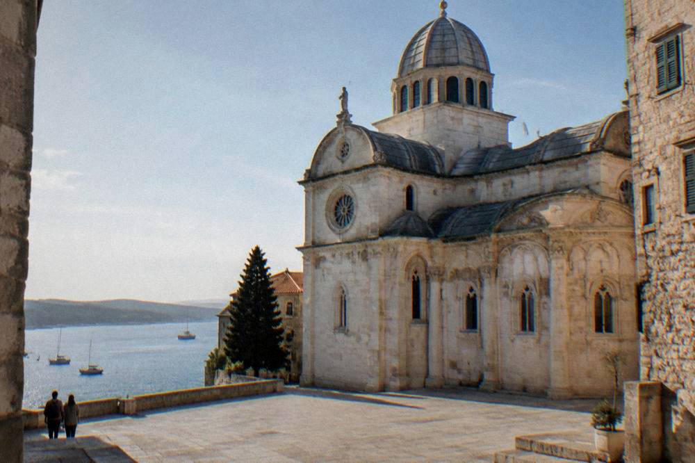 Pale stone cathedral with a rounded roof from a quiet square