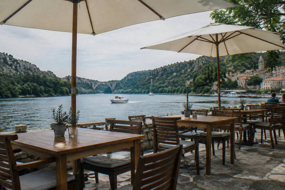 Riverside terrace with empty tables under parasols by the river