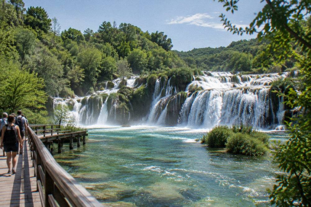 Skradinski Buk waterfall with bright foliage and a boardwalk in summer light