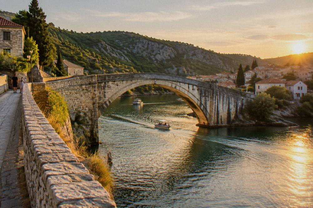 Stone road bridge and green river near Skradin in golden light