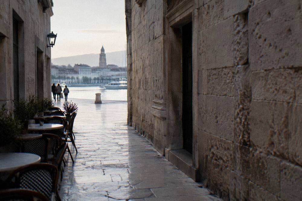 Narrow stone passage of a Roman palace with pale walls and polished paving