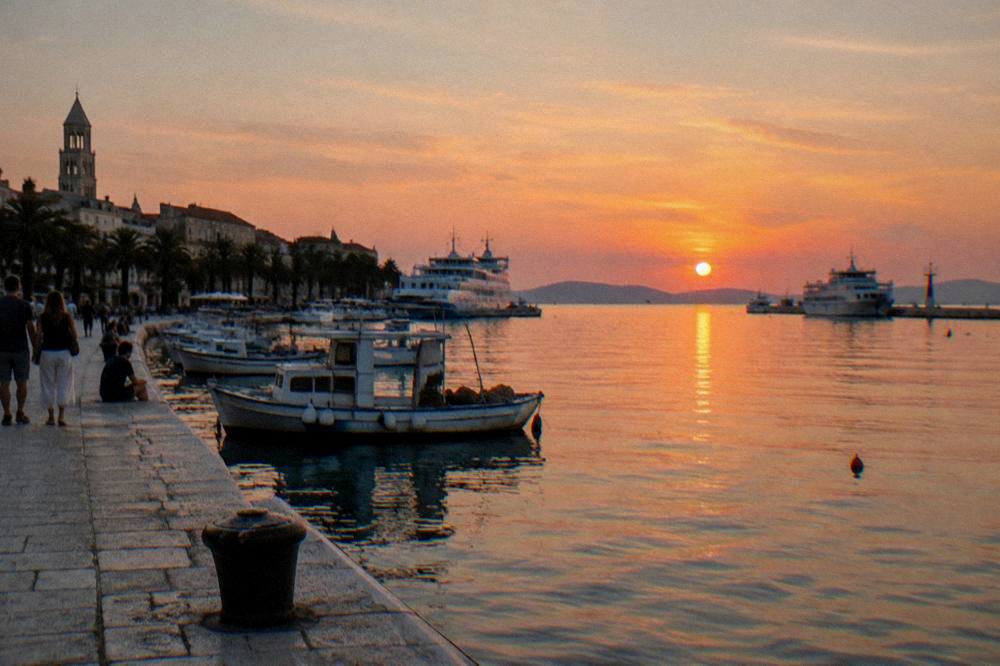 Split harbour with boats and a pale stone quay in evening sun