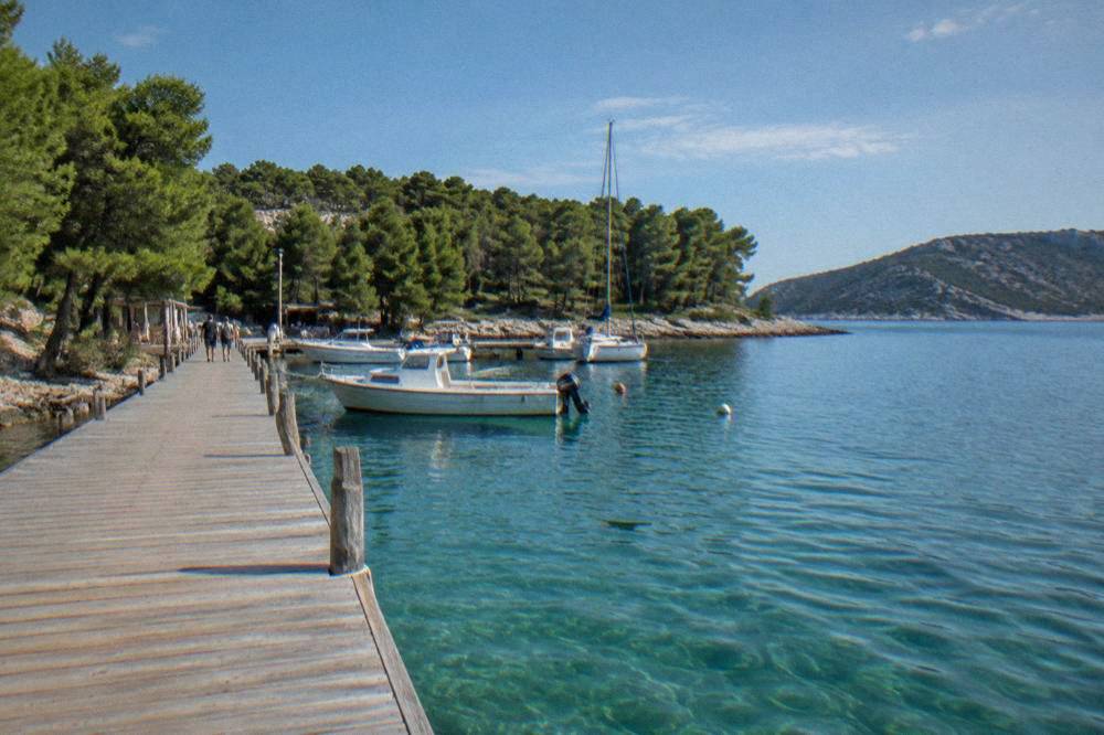 Wooden jetty into clear water at the park entrance with moored boats
