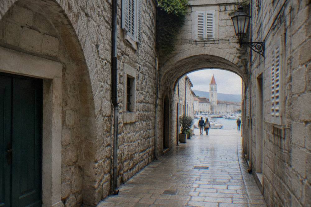 Narrow polished stone lane in Trogir with arched passages on a clear day