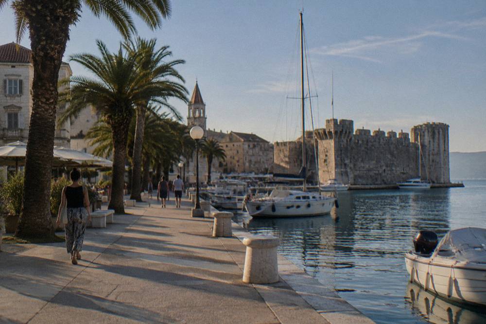Trogir waterfront promenade with palms, yachts and a fortress wall