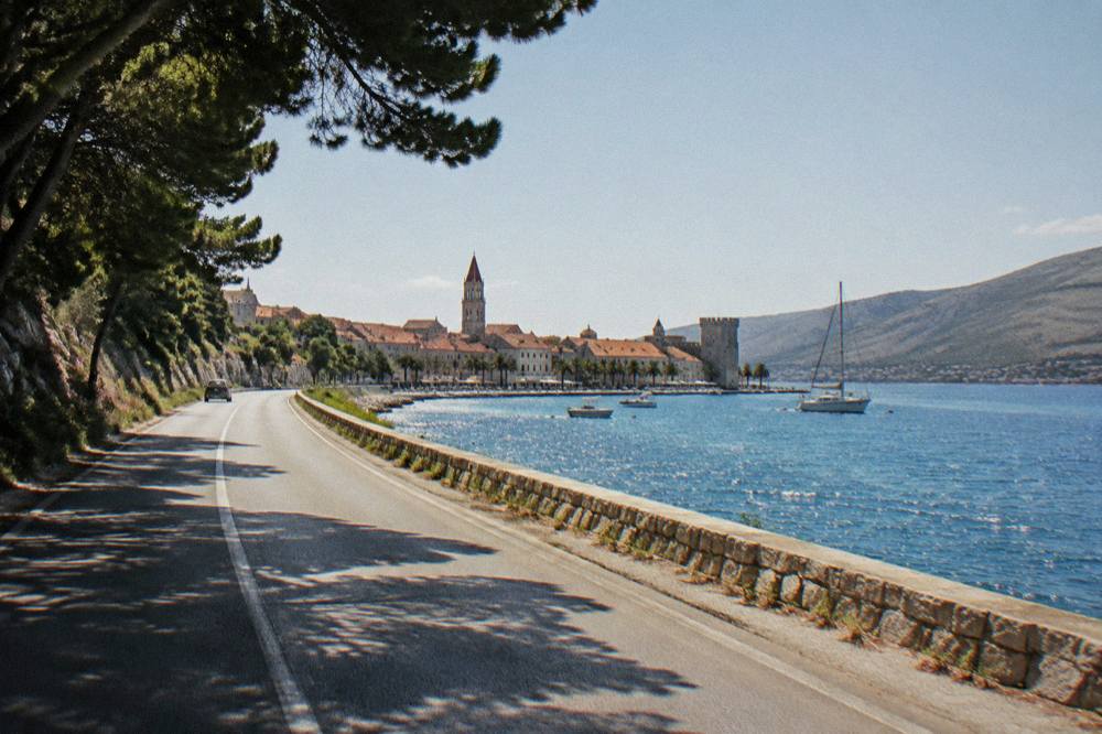 Coastal road toward Trogir with sparkling sea and bare hills