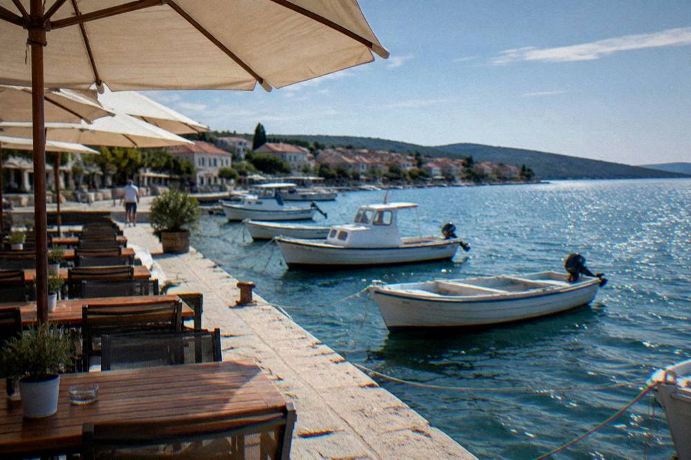 Quayside terrace with empty tables and fishing boats on Ugljan