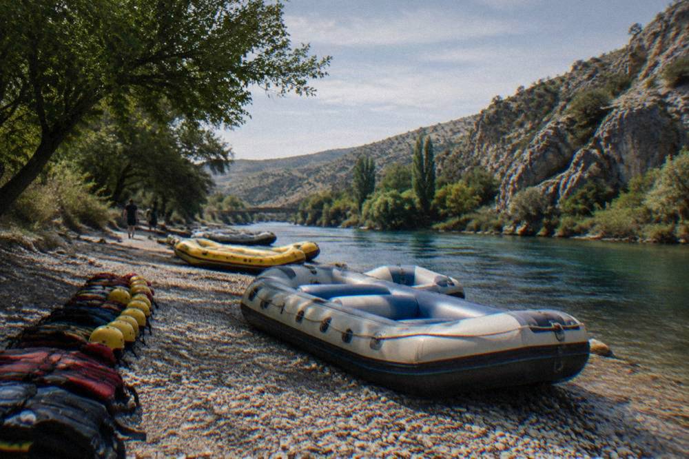 Rafts and helmets lined on a gravel bank beside the river