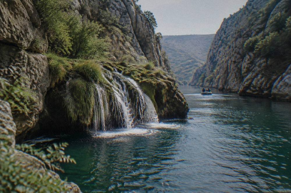Waterfall over a mossy rock ledge into a deep green pool