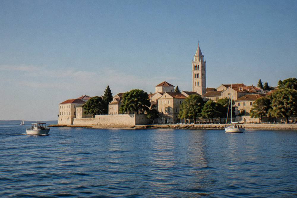 The walled Old Town peninsula of Zadar seen from the water on a bright day.