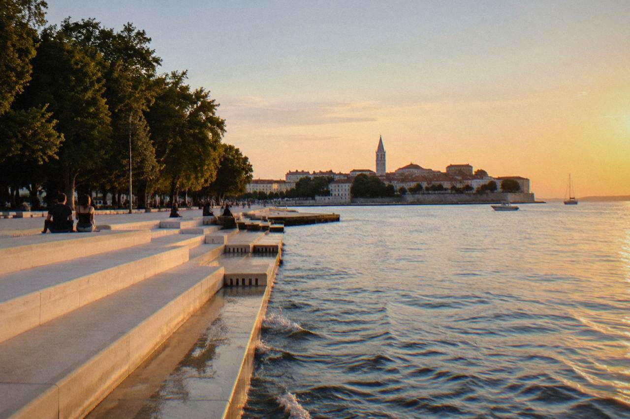 Golden hour light over the Zadar peninsula and glassy sea from the Sea Organ steps.