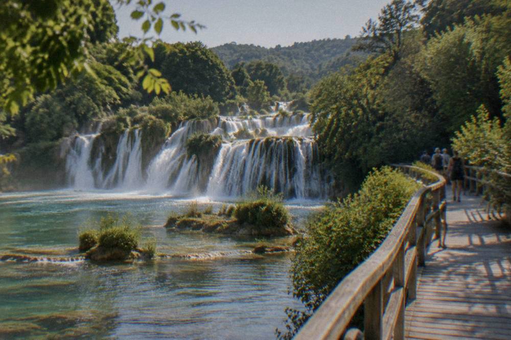 Travertine waterfalls and a wooden walkway among green vegetation at Skradinski Buk.