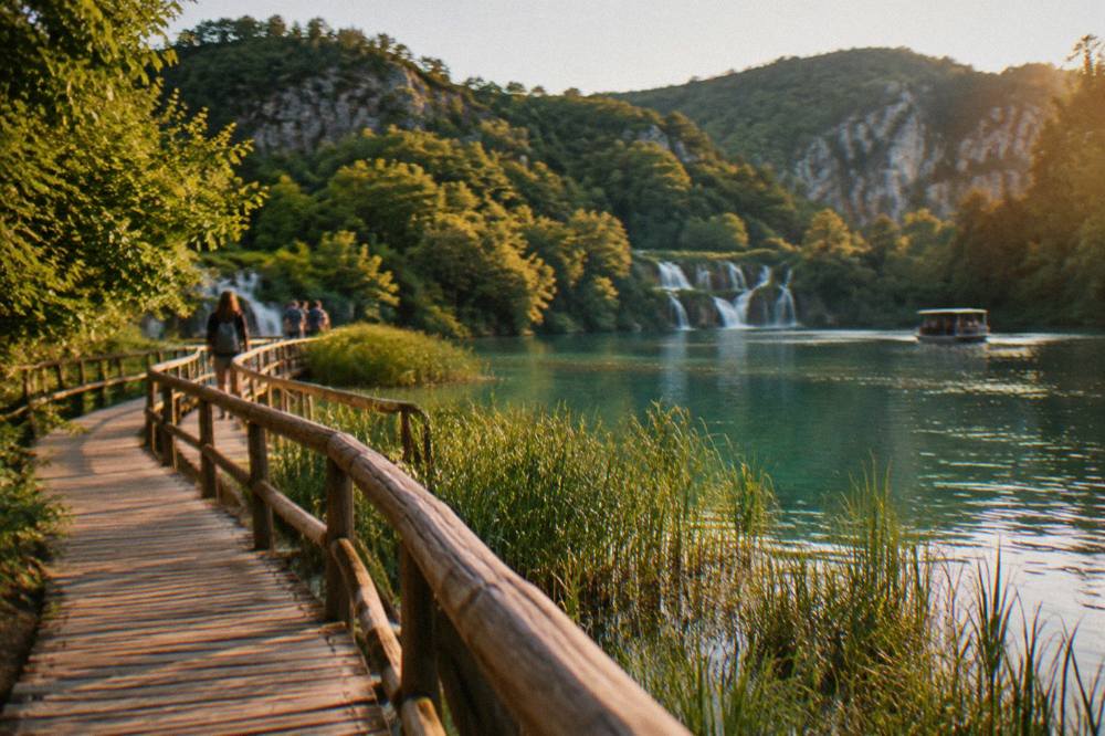 A wooden walkway curving across a turquoise lake in a forested national park.