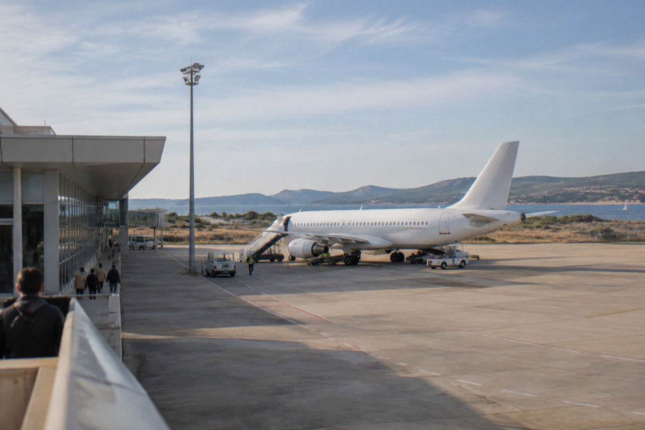 A small coastal airport with a parked airliner on the apron under a clear blue sky.