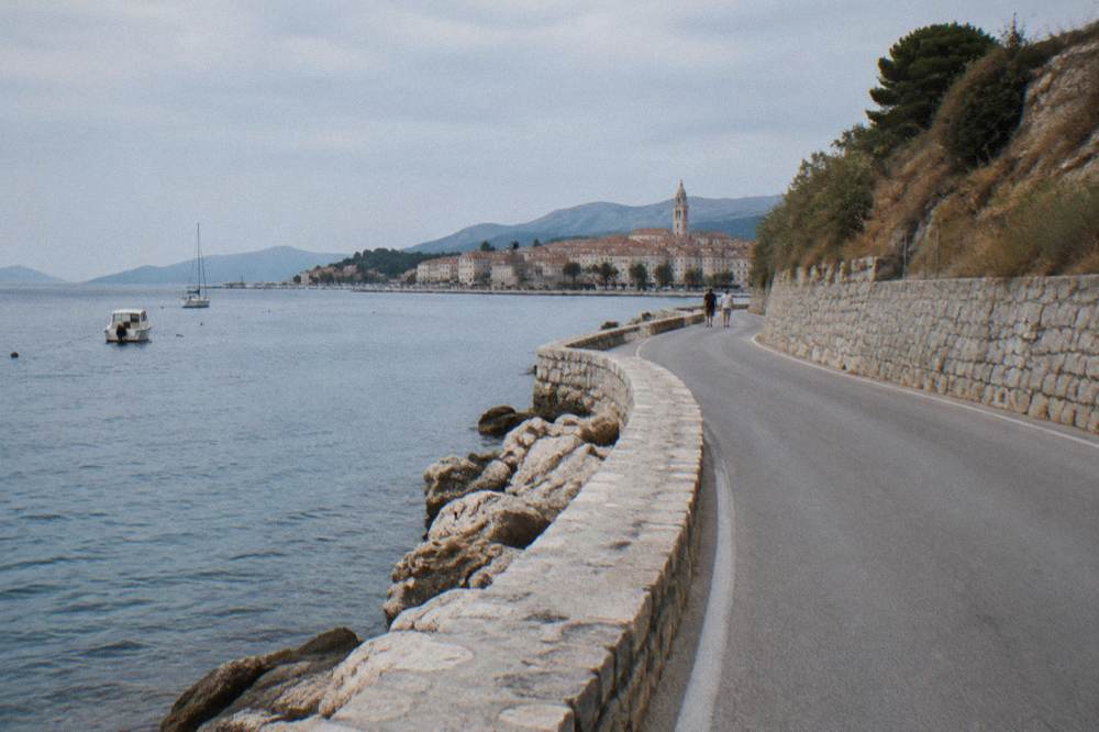 A coastal road winding along the Adriatic past dry hills and stone walls.