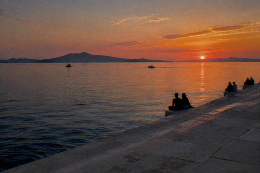 Distant people on the stone steps beside the Sea Organ at dusk.