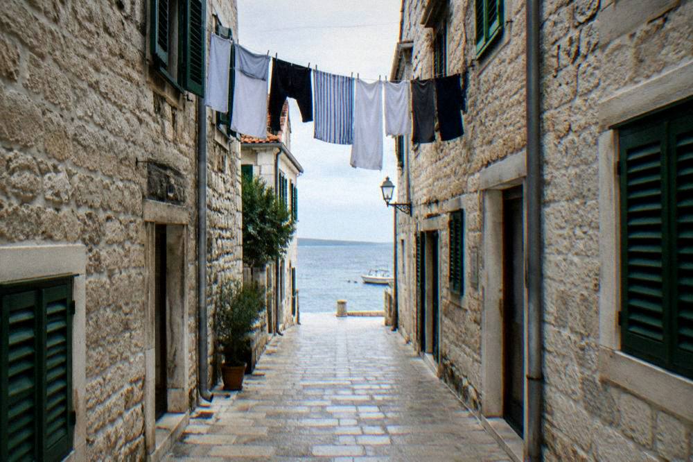 A narrow pale stone lane in Zadar Old Town with laundry hung between upper windows.