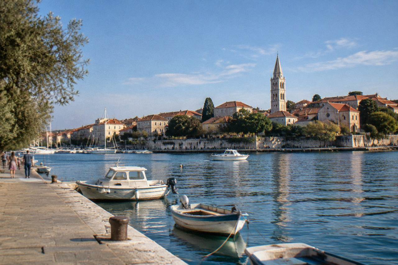 Zadar Old Town rooftops across the harbour at golden hour with a bell tower.