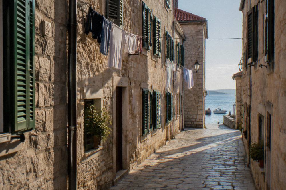 A quiet pale stone lane in Zadar Old Town with laundry strung between windows.