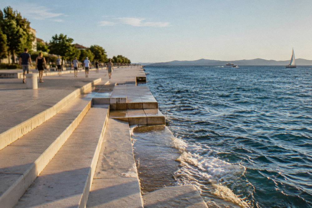 Distant walkers on the seafront promenade beside the Sea Organ steps.