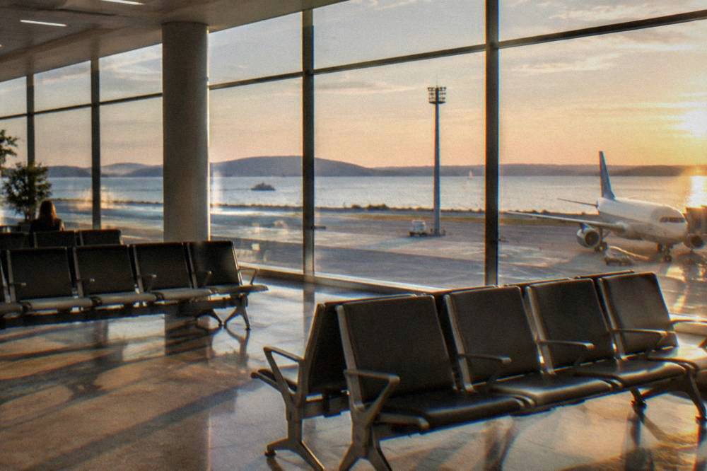 A modern airport hall with bright lighting, empty seats and large windows.