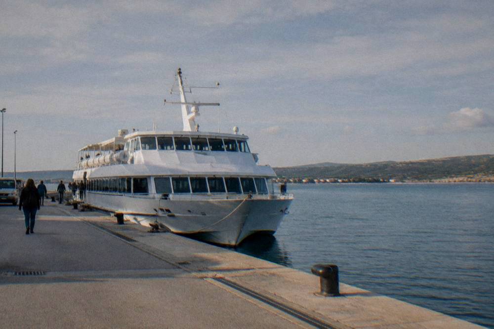 A white passenger ferry tied at a concrete quay with calm blue water behind.