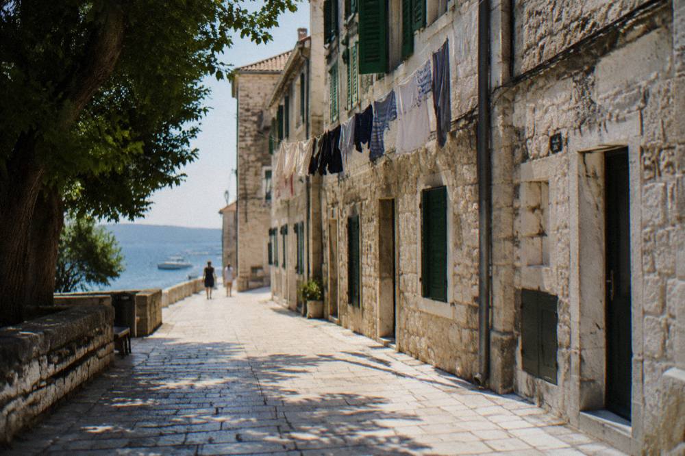 A narrow pale stone lane in Zadar Old Town with laundry hanging between windows.