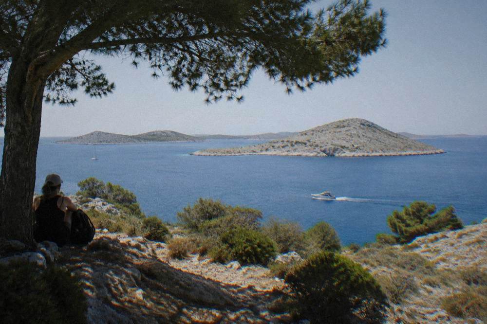 A line of bare stone islands rising from flat blue sea under a clear sky.