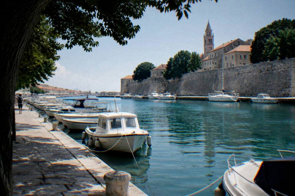 A stone quay with moored boats beside the walled edge of Zadar Old Town.