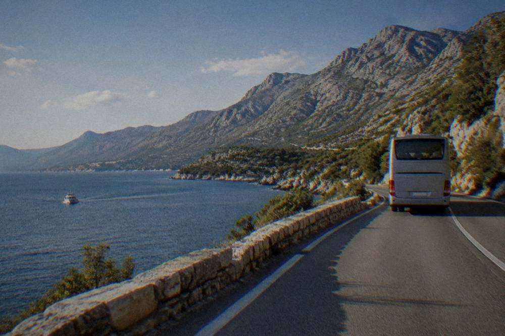 An intercity coach on a coastal road in Dalmatia with the Adriatic beside it.